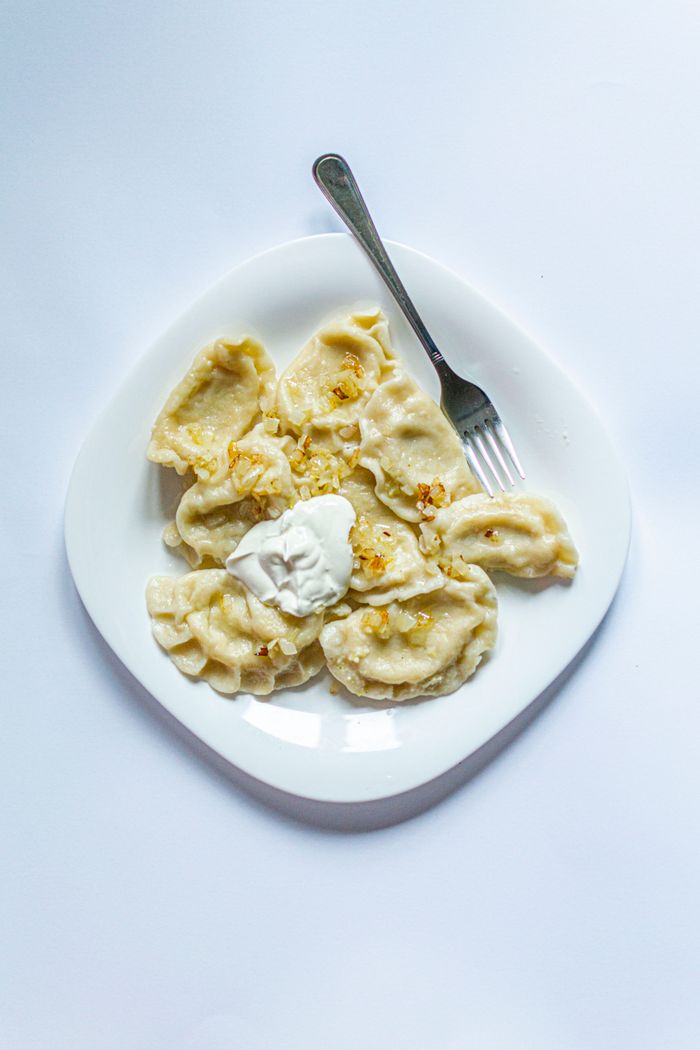 Plate of traditional dumplings topped with sour cream, perfect for a savory meal.