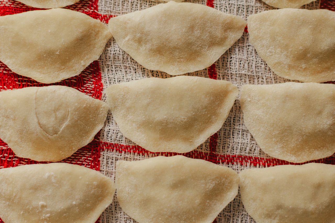 Close-up of homemade dumplings arranged on red checkered fabric, ready to cook.