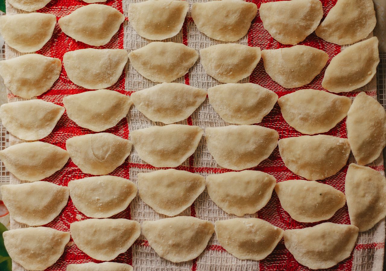 Top view of freshly made dumplings arranged neatly on a red checkered cloth.