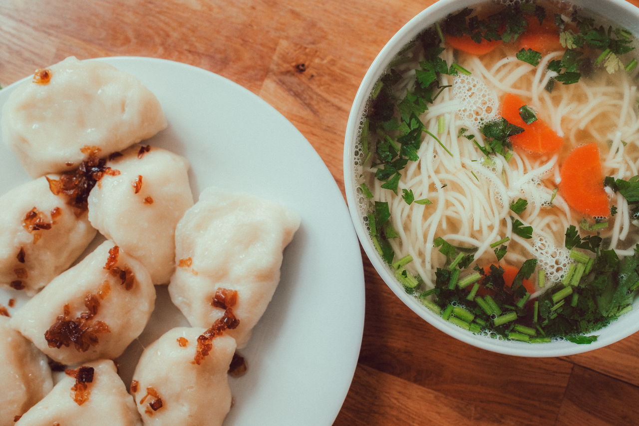 Delicious Polish pierogi with fried onions and noodle soup, perfect for a cozy meal.