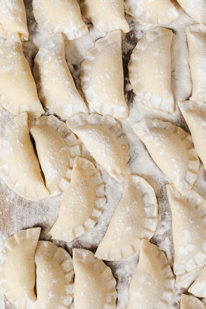 A detailed view of homemade pierogi dumplings laid out on a floured board, ready for cooking.